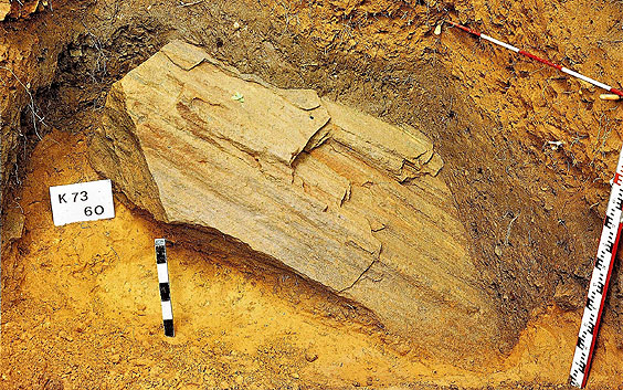 Grand morceau d'un banc de grès ferrugineux, au centre d'une couche archéologique